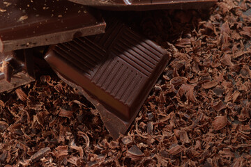 Broken dark chocolate bar and chocolate flakes on black kitchen table