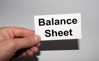 Message on the card BALANCE SHEET in hands of businessman.