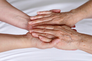 Wrinkled hands of senior woman in the palms of a young woman. Concept of care and support, elderly mother and daughter