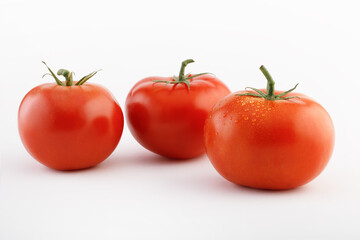 Three tomatoes on a white background with tails