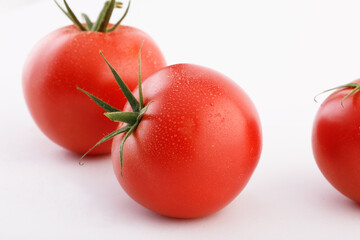 Three tomatoes on a white background with tails