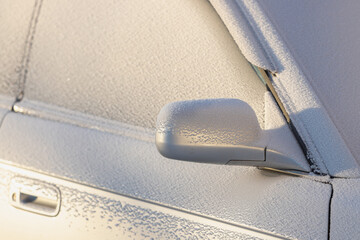 The car body is covered with frost. Windshield and side mirror.