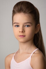 Naklejka premium portrait of a beautiful child girl with long beautiful hair styled in a hairstyle in a pink t-shirt