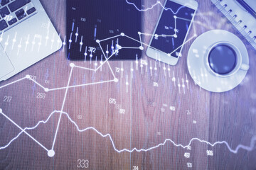 Double exposure of forex graph hologram over desktop with phone. Top view. Mobile trade platform concept.