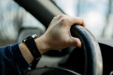 Close-up of a male hand on steering wheel in a modern car in the UK steering wheel on the right 