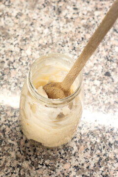 Wooden kitchen spoon in a glass jar with raw pork lard top view isolated