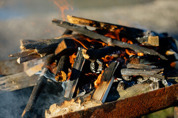 Flaming coals in a portable summer barbecue with the empty grill on top outdoors in the garden with sparkling sunlight bokeh