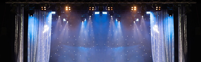 An empty stage of the scene concert hall, lit by spotlights and smoke 