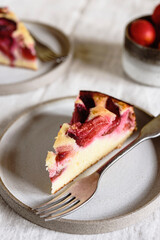 Slices of Homemade Ricotta Plum Cake on plates on beige linen tablecloth. Cottage cheese casserole with vanilla, semolina and plums. Selective focus