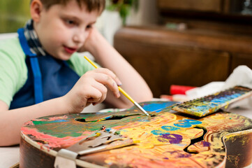 kid have fun painting guitar. color gouache art therapy lesion.