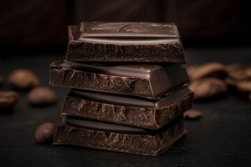 dark chocolate close-up pieces of cubes on the table. black background, candy