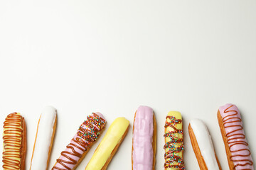 Tasty eclairs with different topping on white background