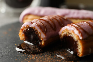 Tasty eclairs with delicious topping on black tray, close up