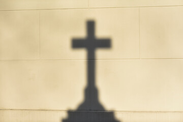 The shadow of the Christian cross on the wall. Selective focus.