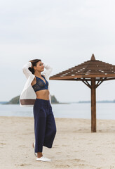 Trip and journey concept. Philosophical photo of modern young woman at beach. Minimalism style at clothes  