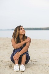 Trip and journey concept. Philosophical photo of modern young woman at beach. Minimalism style at clothes  