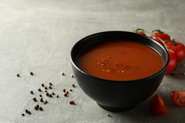 Bowl of tasty tomato soup on gray background
