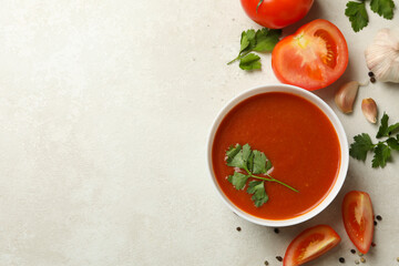 Bowl with tomato soup and ingredients on light background