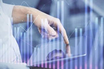 Double exposure of man's hands holding and using a digital device and forex graph drawing. Financial market concept.