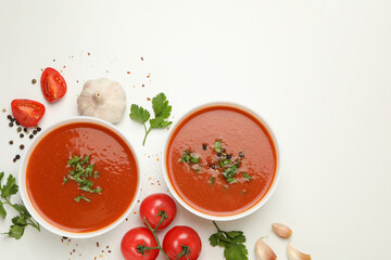 Bowls with tomato soup and ingredients on white background