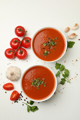 Bowls with tomato soup and ingredients on white background
