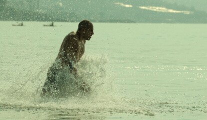 man running into the water at a beach