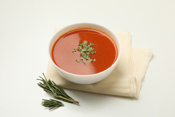 Bowl of tomato soup and towel on white background