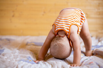 A funny playing cute baby in the amber baby necklace  trying to stand up  doing exercisesm stading on his head and hands back to front