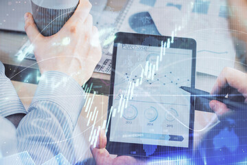 Double exposure of man's hands holding and using a phone and financial chart drawing. Market analysis concept.