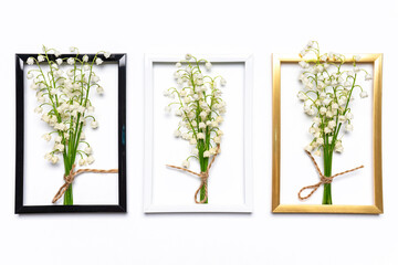 Three small bouquets of lilies of the valley flowers in golden, white and black frames on white background. Creative spring composition in minimal style. Flat lay, top view, copy space