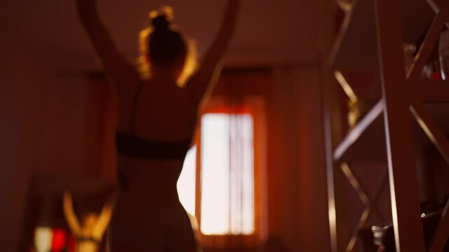 silhouette of sensual unrecognizable woman in lingerie in bedroom against window with sunset sunlight. brurred footage