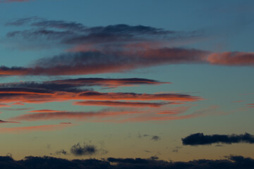 sky with unusual amazing clouds of rich and soft colors at sunset