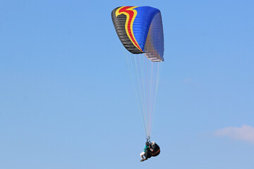 Tandem Paraglider flying wing in a blue sky	