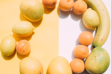 Apricot, lemon and mango fruit on white and yellow background