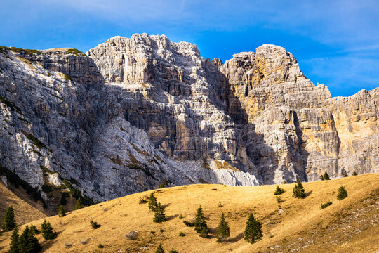Panorama with blue sky, rocky mountains and tree-lined slopes. Sass de Mura and Monte Alvis. Cesiomaggiore, Belluno, Italy