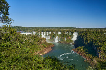 Fototapeta na wymiar Iguazu Falls or Iguacu Falls, on the border of Argentina and Brazil, are the largest waterfall in the world. Very high waterfall with white water in beautiful rain forest landscape in the jungle