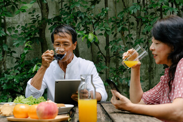 Old couple having breakfast together at backyard in holiday.