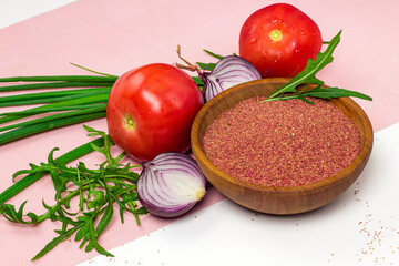 Red or pink amaranth seeds in wooden bowl and fresh vegetables. Amaranth grain, tomatoes, onion and arugula on white background. Organic, healthy food
