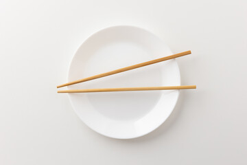 A white empty plate with chopsticks on the plate