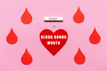 Red heart and red drops on pink background. Text JANUARY IS BLOOD DONOR MONTH. Annual national red cross campaign in January, 2021. Charity, donation, volunteer concept. Healthcare and medicine