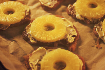 Steaks with pineapples on top before cooking, toned
