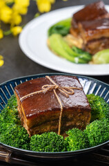 Dong Po Pork meat in a blue plate with broccoli in black background.
