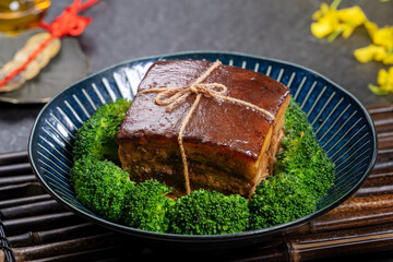 Dong Po Pork meat in a blue plate with broccoli in black background.