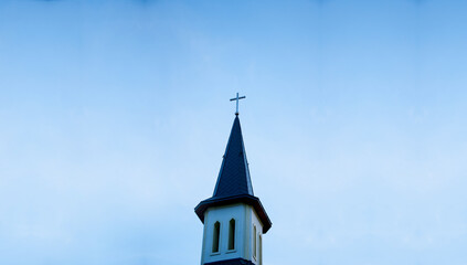 Church building. Spire of the Catholic Church with a cross. Against the background of the blue sky. Protistantism