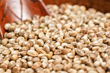Unpeeled hemp - Cannabis sativa - in small dark wooden bowl cup with spoon, closeup detail