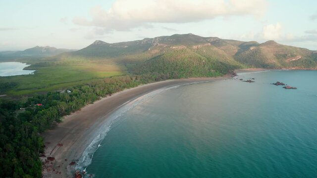 Aerial drone image at sunrise over Cape Hillsborough with blue water and green rainforest and nice morning warm sunlight