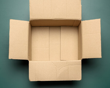open empty cardboard rectangular box made of corrugated brown paper on a green background