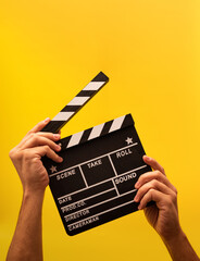 Naklejka premium Isolated movie clapperboard gripped by male hands on yellow background