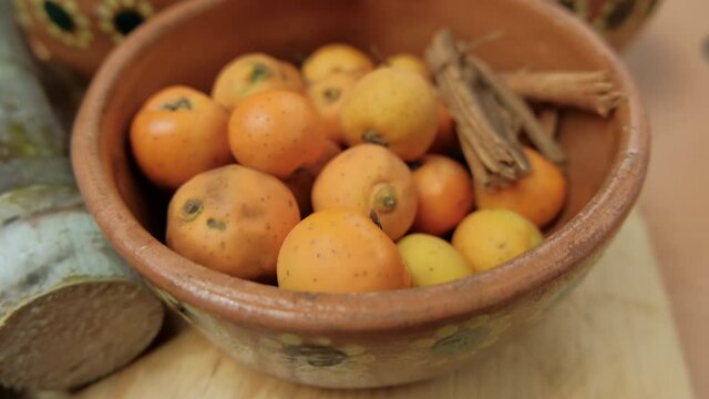 Fresh Mexican hawthorns and cinnamon sticks in a clay bowl