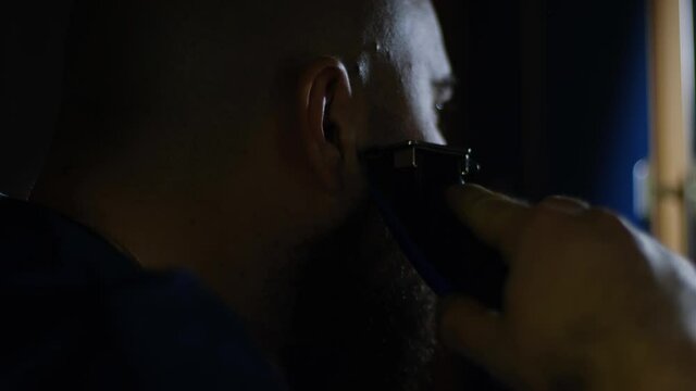 A man shaves off his beard with a shaving machine, close-up. The concept of changing the image and style